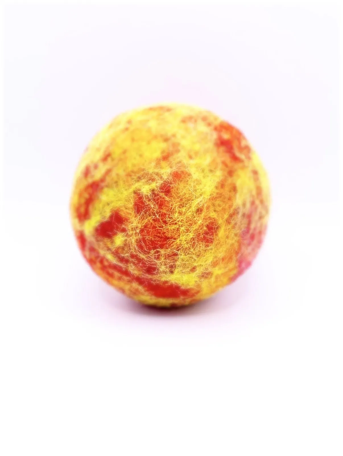 A round yellow and orange needle-felted sun on a white background